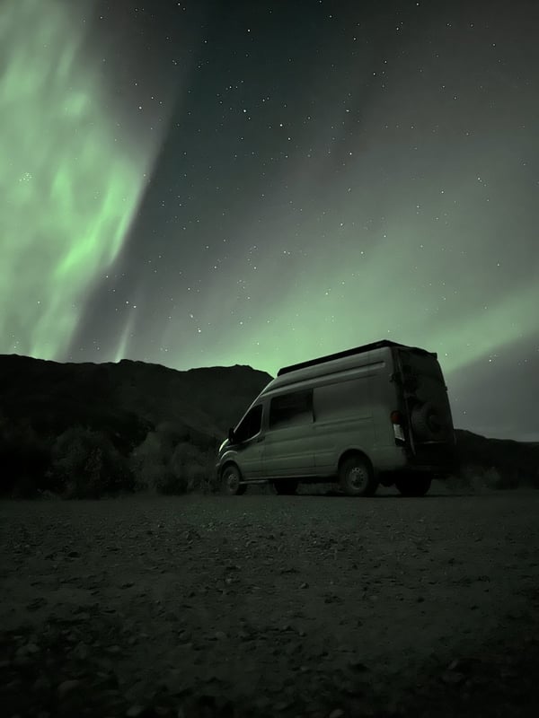 The van parked under northern lights on the Dempster Highway